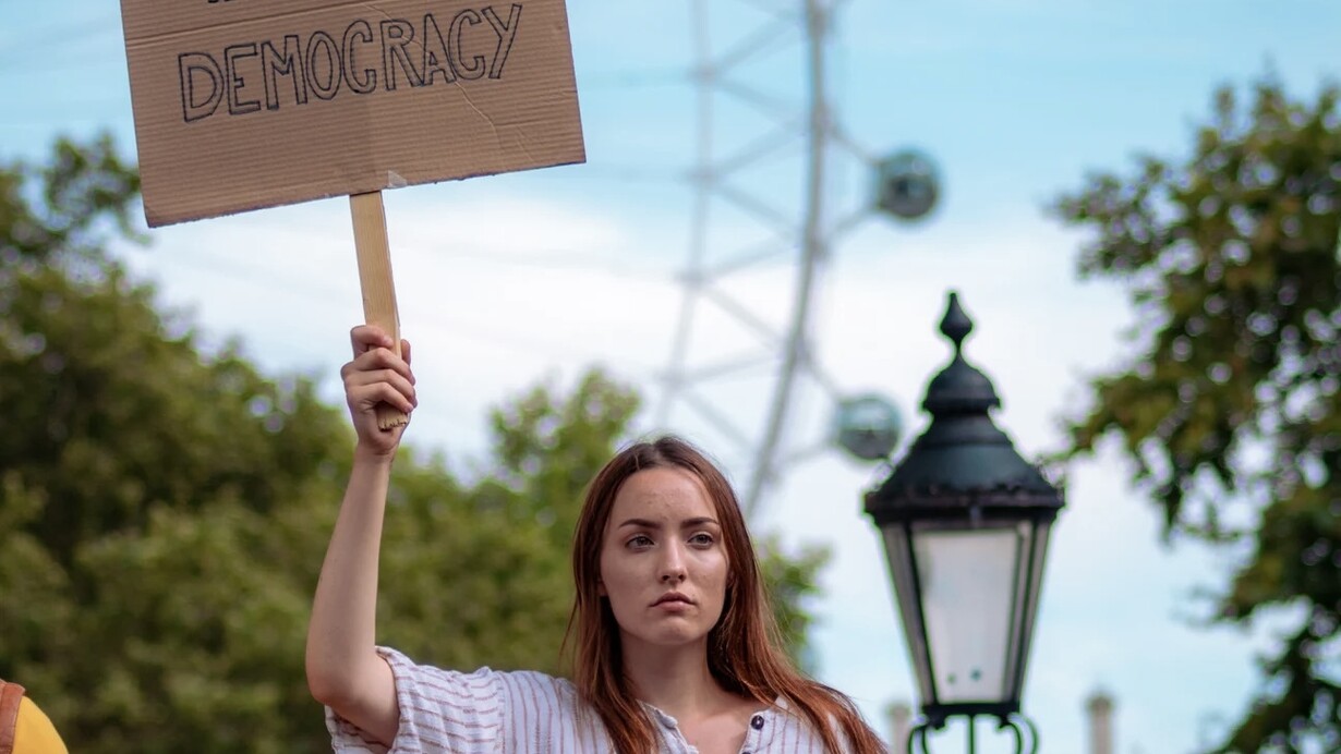 Une femme tenant une pancarte et exigeant la démocratie