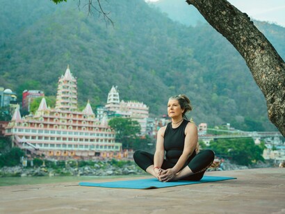 Diplomacy can unfold on a yoga mat, where stillness, presence, and connection create lasting bonds. Woman practicing yoga by the river in Rishikesh, India