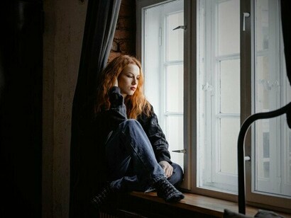 A woman staring out at the world she longs to enter, echoing the silent wish for connection