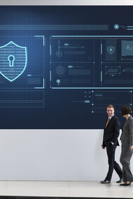 Businesspeople walking by a large cybersecurity advertisement displayed in a modern business area