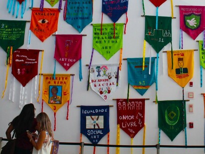 Exposição temporária no Museu do Amanhã, "Estandartes dos Direitos Humanos". Rio de Janeiro, Brasil, 2018. No PIDESC estão agrupados os direitos económicos de viver livre da fome, a um padrão de vida mínimo com vestuário e moradia, ao trabalho; nos direitos sociais dá relevo à segurança social das famílias, o acesso aos serviços de saúde física e mental