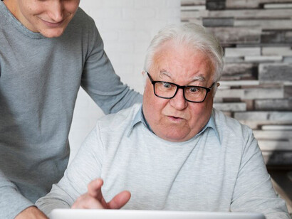 An elderly man learning to use a digital device with AI support for dementia