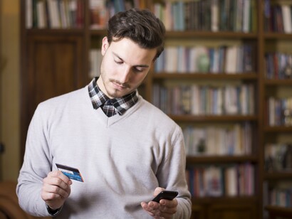 Un joven introduce su número de tarjeta de crédito para pagar una compra