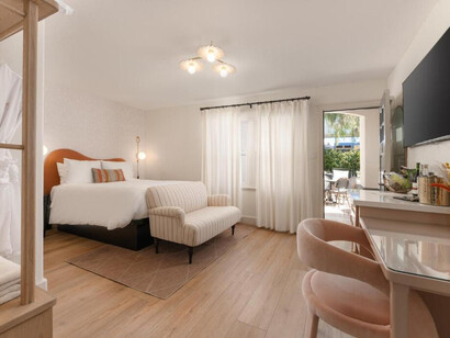 The room features a large bed with crisp white bedding and an arched, warm terracotta-colored headboard