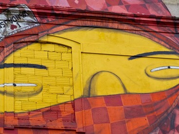 Obra sem título, mas reconhecida pelo nome "I love vandalismo", de Os Gêmeos, realizada em 2010 na Avenida Fontes Pereira de Melo, em Lisboa, Portugal. O detalhe evidencia o rosto amarelo do personagem encapuzado, cercado por formas vermelhas e geométricas que se integram à arquitetura do edifício. A intervenção faz parte do Projeto CRONO, que levou a arte urbana de grande escala para fachadas degradadas da capital portuguesa