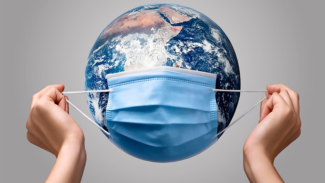 A person placing a medical mask on a globe, symbolizing global health awareness and protection