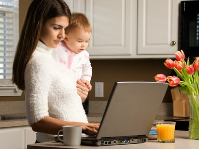 Una madre trabajando con su hija en brazos