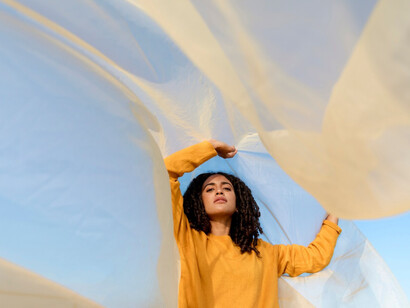 A women using a draped cloth to resemble a moment of emergence
