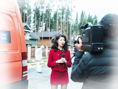 A female news anchor films live at the scene of a crime in a residential neighborhood