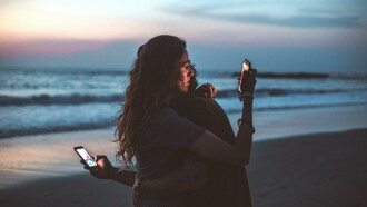 Casal usando o celular abraçados