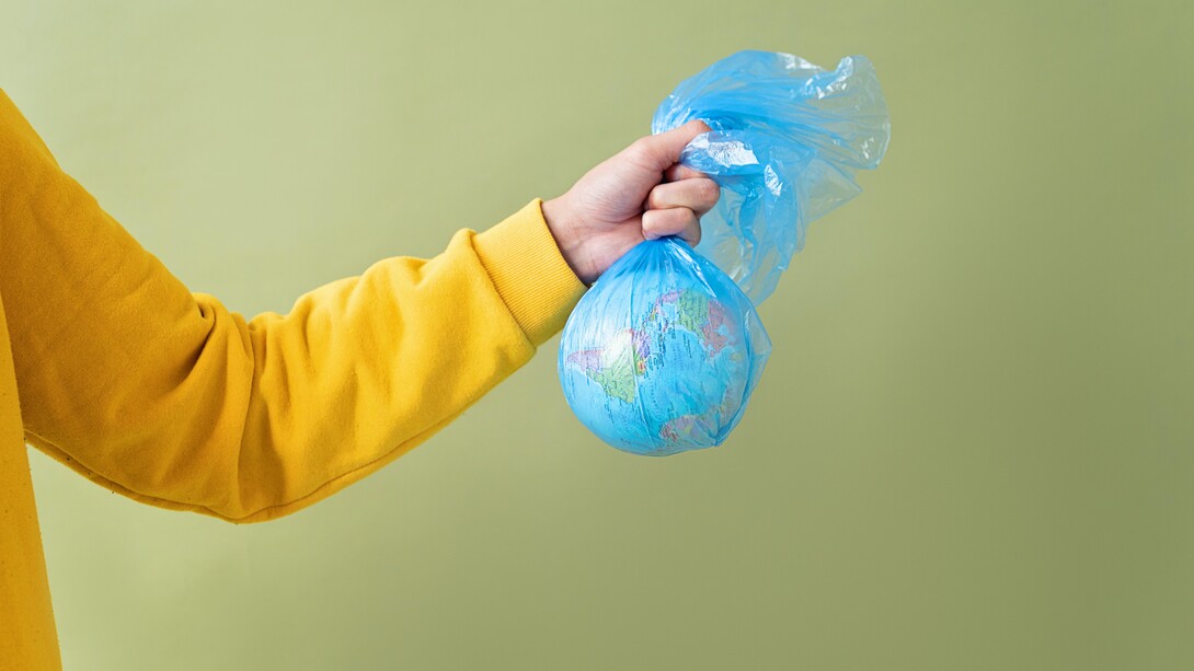 Pessoa segura um globo do planeta terra em sacola plástica