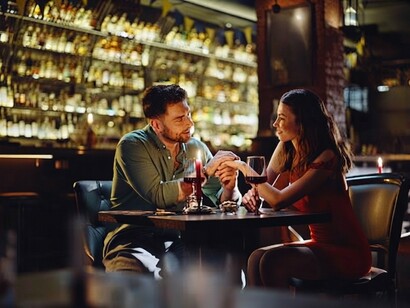 A couple shares a tender moment while dining together in the intimate atmosphere of a modern restaurant