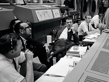 Centre de contrôle de mission dans le centre spatial Johnson, à Houston, au Texas, États-Unis en 1966. Autour du vol Gemini-11, ingénieurs et astronautes échangent en pleine concentration. Christopher C. Kraft Jr., Charles W. Mathews et Donald K. Slayton coordonnent les opérations aux côtés des astronautes William A. Anders et John W. Young, au cœur de la prise de décision spatiale. Photo prise pas la NASA

