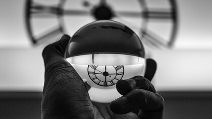 Orologio riflesso in una sfera. Tempo e immutabilità: una prospettiva esistenziale sull'inesorabile scorrere degli attimi