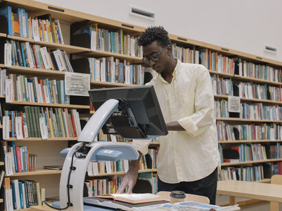 Professor utiliza um equipamento digital para enviar as páginas do livro a ser debatido durante a aula