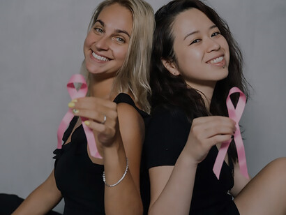 In a powerful display of unity, two women delicately clutch pink ribbons, embodying a shared commitment to raising awareness about cancer and promoting overall health