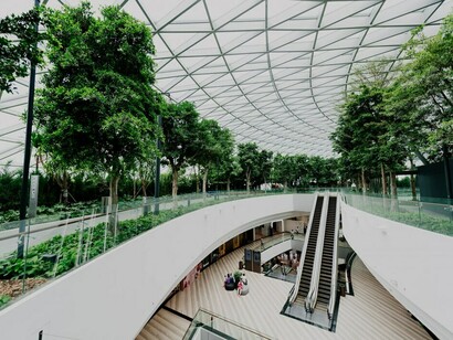 The interior, featuring plants and water elements, exemplifies biophilic design in healthcare architecture, creating a calming and healing environment in hospital spaces
