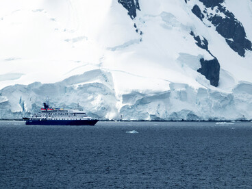 Ice sheet and snowcapped mountains under dark clouds in Antarctic