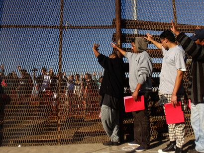 A group of recently deported immigrants stand near the double steel fence that separates San Diego and Tijuana at the border in Tijuana December 10, 2011.
REUTERS/Jorge Duenes