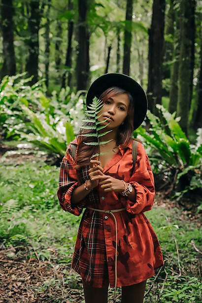 In the heart of nature, a solitary woman gracefully explores the enchanting depths of a verdant forest, surrounded by the soothing embrace of green foliage