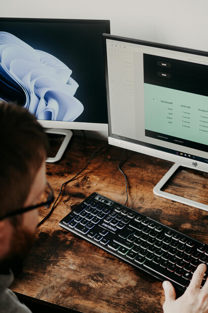 A man seated at a desk, typing code on his computer