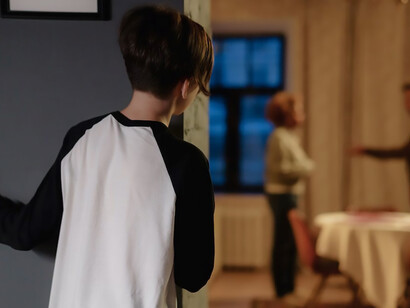 In the background, a child watches with concern as his parents argue, their conversation filled with tense words and unfavorable language