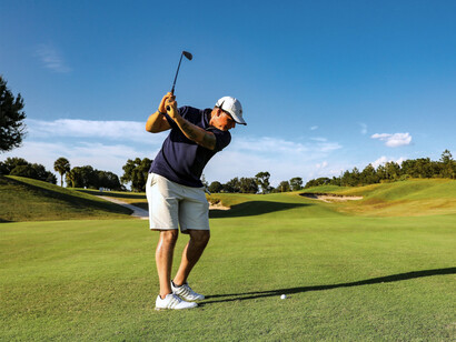 A golfer lining up a powerful swing on a championship fairway, representing the world-class golfing experiences at French Lick Resort, Indiana