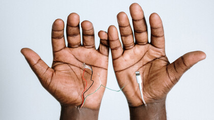 Mãos conectadas a cabos como se fossem partes de suas veias