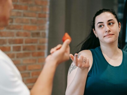 A woman exercising and being offered a strawberry