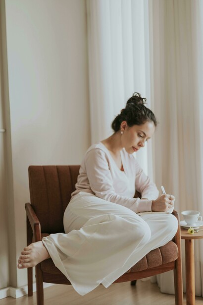 A woman journaling in a cozy apartment interior, focused on inner healing and relaxation