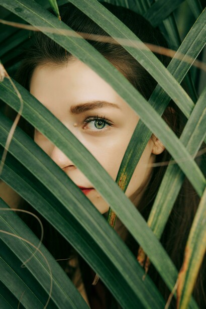 Close-up of a woman’s face framed by green leaves, representing the journey inward to find one’s true purpose