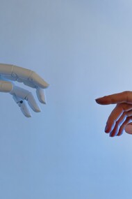 Mão de robô representando a inteligência artificial e mão de um humano