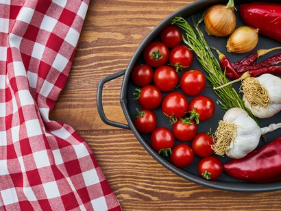 A picnic tablecloth next to a skillet of fresh vegetables that's triggering a fond memory