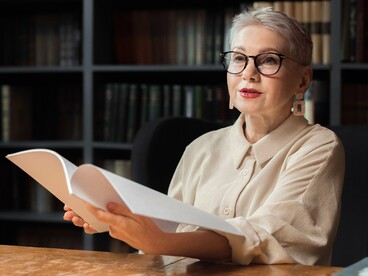 A scholar carefully examining historical manuscripts in a library, representing the study of Katharevousa as the bridge between Ancient and Modern Greek