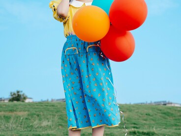 A young girl standing alone with a cluster of balloons, reflecting the uncertainty of holding on to connection while fearing it may disappear