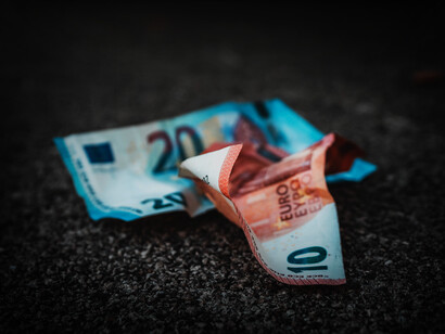 Un billete de 20 y 10 euros arrugados en el asfalto, simbolizan la perdida de valor de la divisa de la 'zona euro'