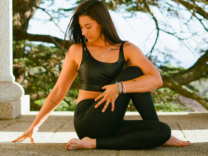 A woman stretching in a building setting with trees in the background