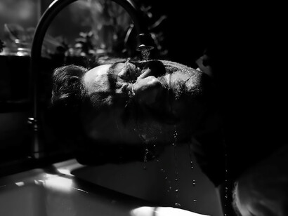 A captivating image captures a man submerged under the steady flow of water from a tap, evoking a powerful visual representation of immersion and the omnipresence of this life-sustaining element