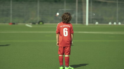 “A faceless teenage football player standing on the field