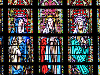 Vibrant stained glass windows honouring female saints, representing the spiritual foundations that coexist with cultural tradition