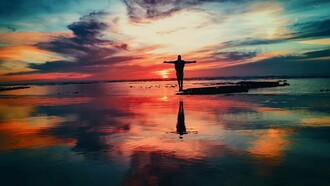 Channeling life with arms stretched out as the sun sets