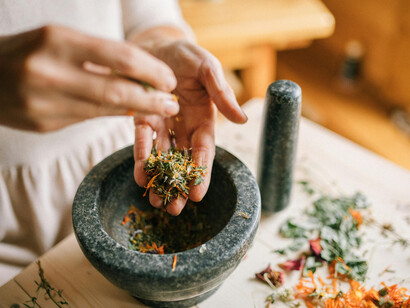 Hands preparing a herbal infusion with a mortar and pestle