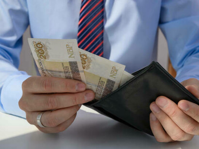 A man holds up his empty wallet, symbolizing the struggle of poverty and the importance of fair wages for a sustainable living