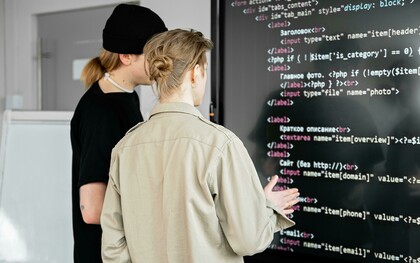 Two men reviewing code on a board, illustrating collaborative coding and the use of AI tools in development