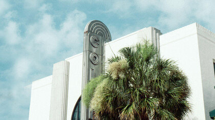 An art deco front face of a Miami building, and their notable palm trees