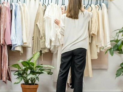 Mulher escolhe roupas em arara de loja de moda circular, abordagem regenerativa onde o vestuário e os têxteis são concebidos, produzidos e consumidos visando minimizar o desperdício, a poluição e a utilização de recursos naturais. É preciso olhar para o processo de produção como um todo, considerando os colaboradores envolvidos em cada etapa, como são remunerados, como são amparados (em termos de saúde e segurança do trabalho), que tipo de matéria – prima será utilizada na produção, quais os processos envolvidos e os impactos causados à sociedade e ao meio ambiente, entre outros fatores