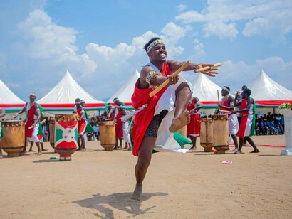 A dancer in Burundian ceremonial dress performing a traditional routine, representing the cultural roots that establish community belonging