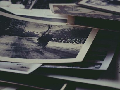 Cartoline con fotografie ingiallite adagiate su una scrivania invocano ricordi