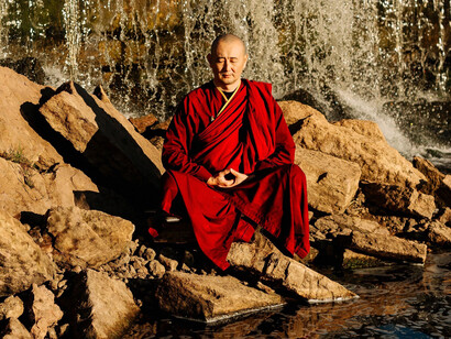 A monk immersed in silent meditation against the backdrop of a waterfall, reflecting the pursuit of inner peace through presence