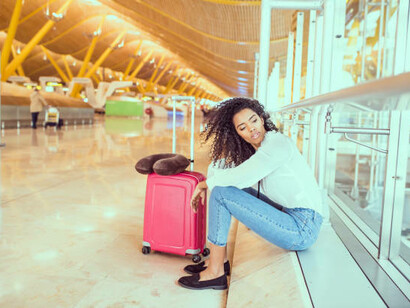 A woman working on her laptop at the airport, waiting by the window—an expat on the move